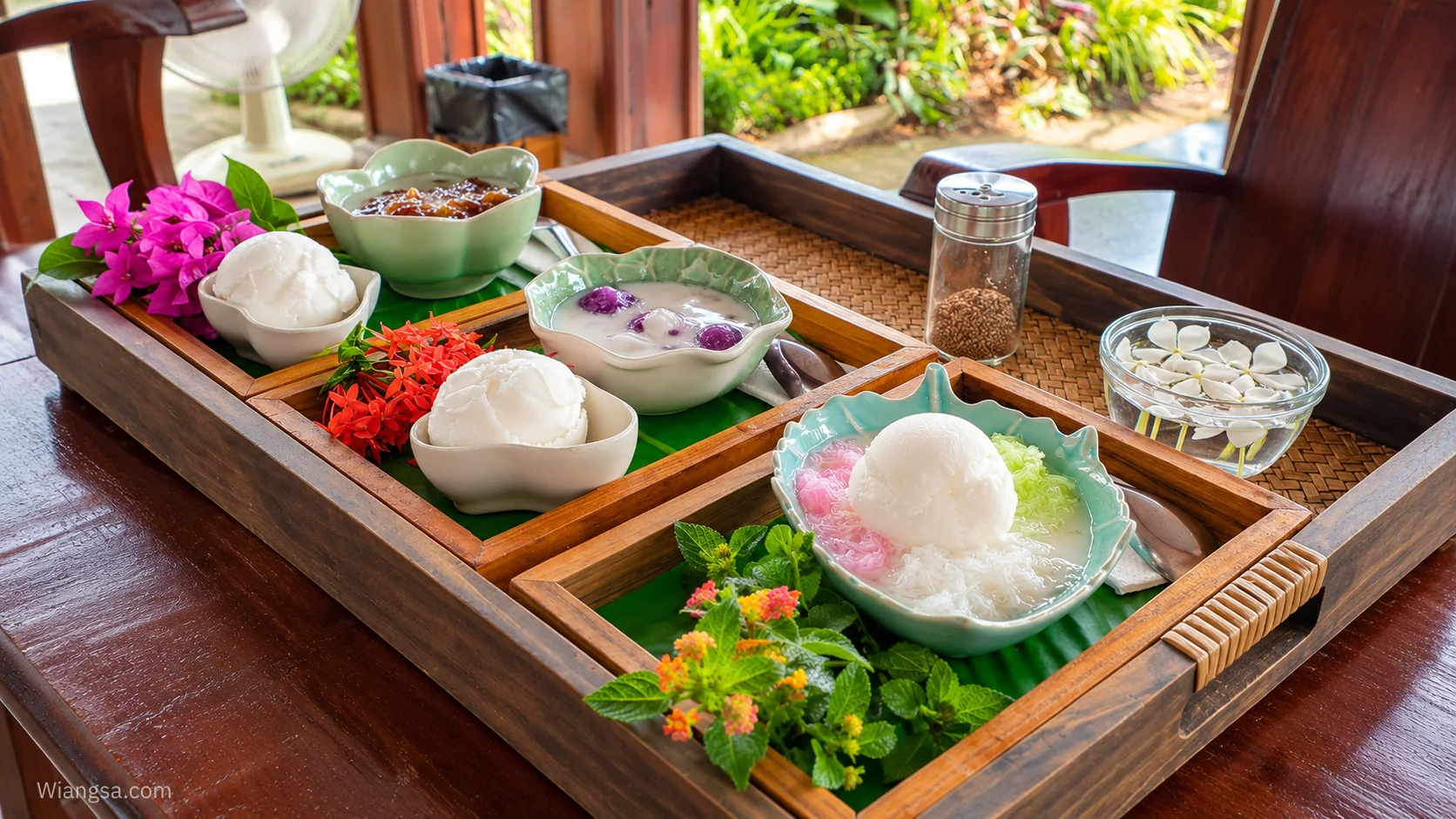 ถาดขนมไทยจัดในถ้วยสีเขียวอ่อนบนถาดไม้ประดับดอกไม้