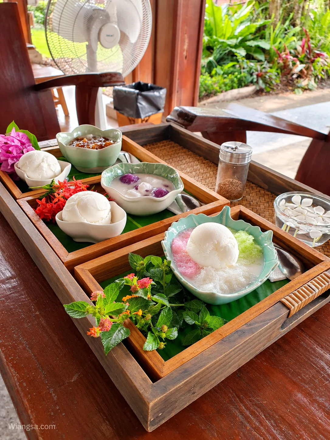 ขนมไทยและของหวานเย็นบนโต๊ะไม้ พร้อมดอกไม้ตกแต่ง