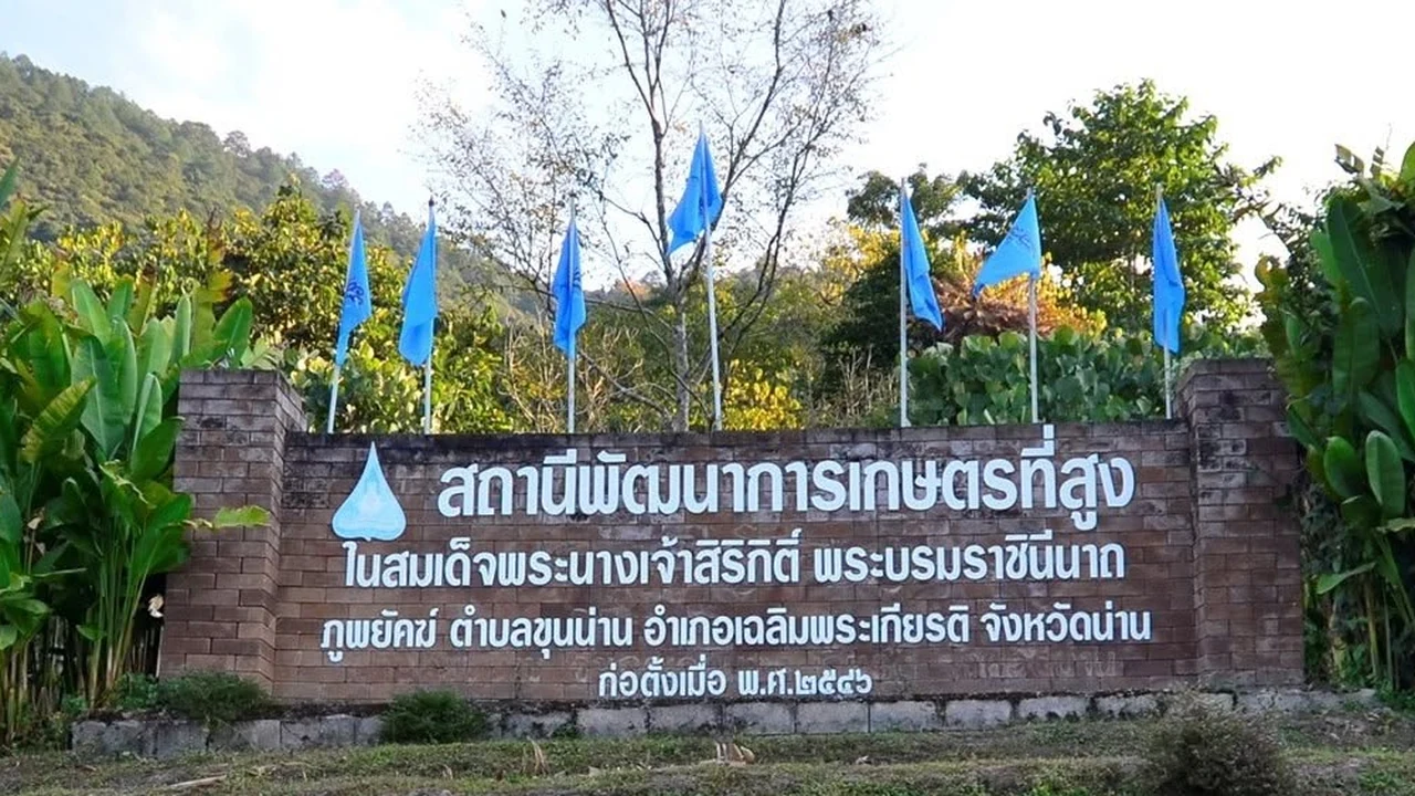 ป้ายอิฐสถานีพัฒนาการเกษตรที่สูงภูพยัคฆ์ มีชื่อสถานีและที่ตั้งตำบลขุนน่าน พร้อมธงสีฟ้าด้านหลัง