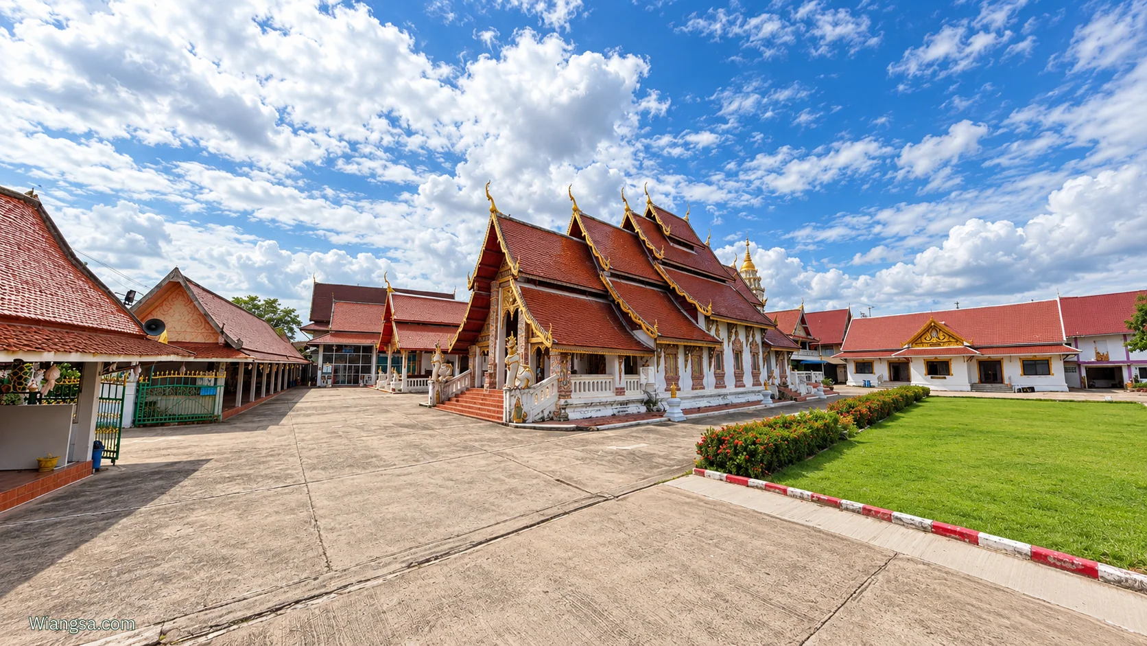 ภาพมุมกว้างวิหารวัดบุญยืน พระอารามหลวง หลังคาซ้อนชั้นสีแดง ขอบปูนสีขาว ลานวัดและสนามหญ้า