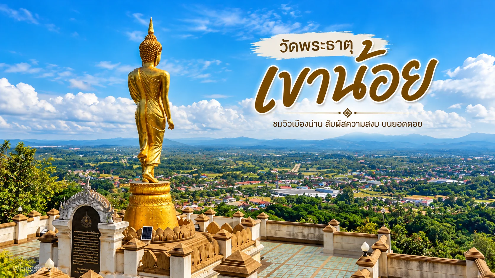 พระพุทธรูปสีทองมองไปทางเมืองน่านจากลานบนเขาน้อย มีท้องฟ้าและภูเขาอยู่เบื้องหลัง