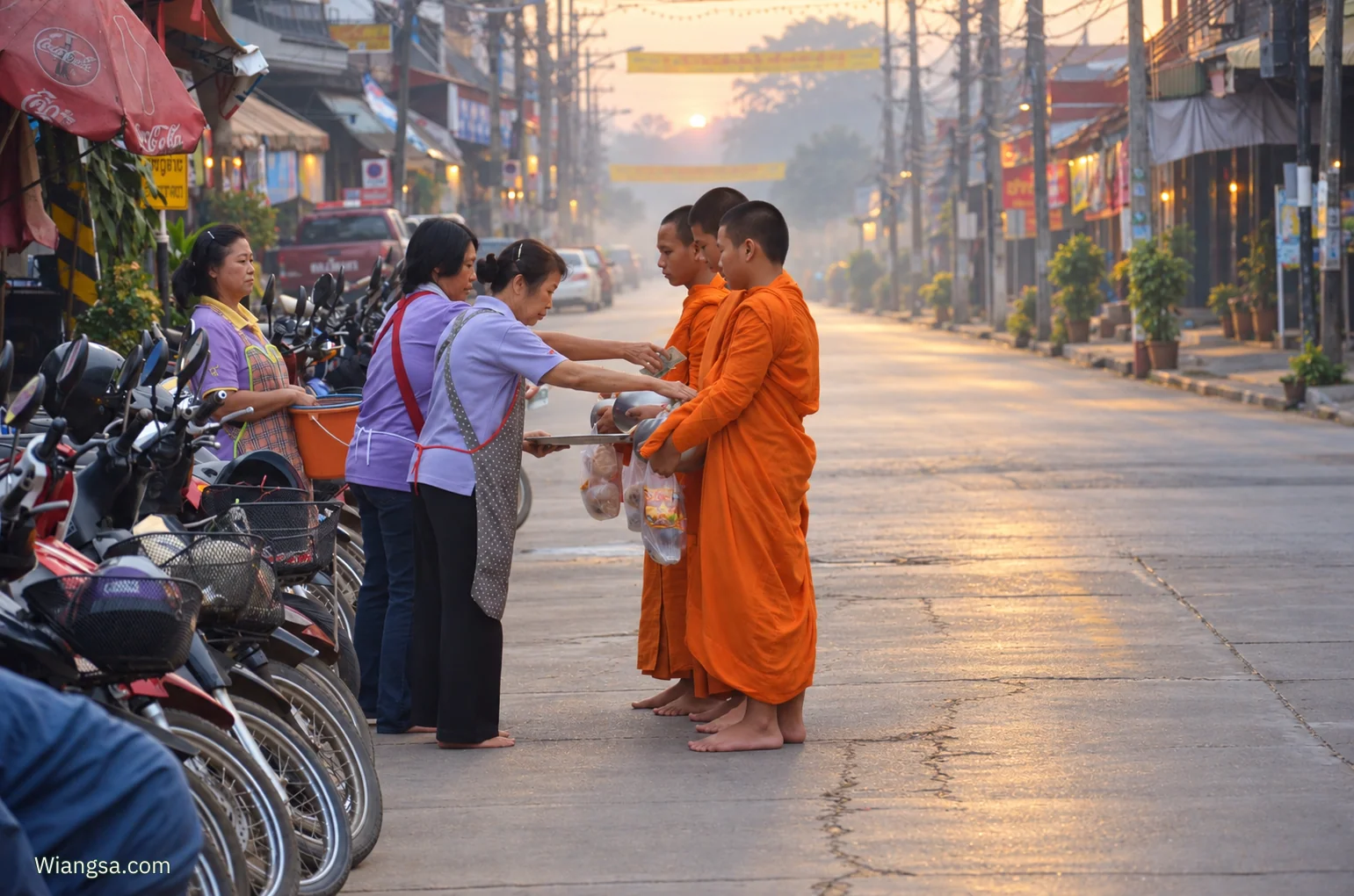ภาพบรรยากาศการใส่บาตรในย่านตลาดเช้าเวียงสา พระภิกษุในจีวรสีส้มรับอาหารจากชาวบ้านบนถนนยามรุ่งสาง